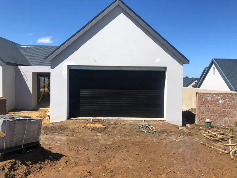 Dark garage door spanning a double-width opening at a new build
