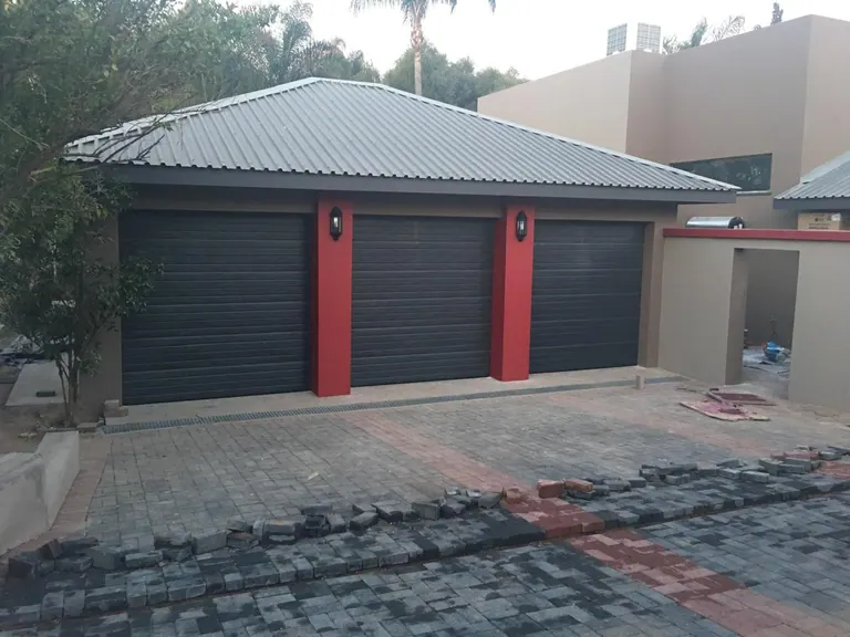 Three separate dark garage doors with red dividing columns